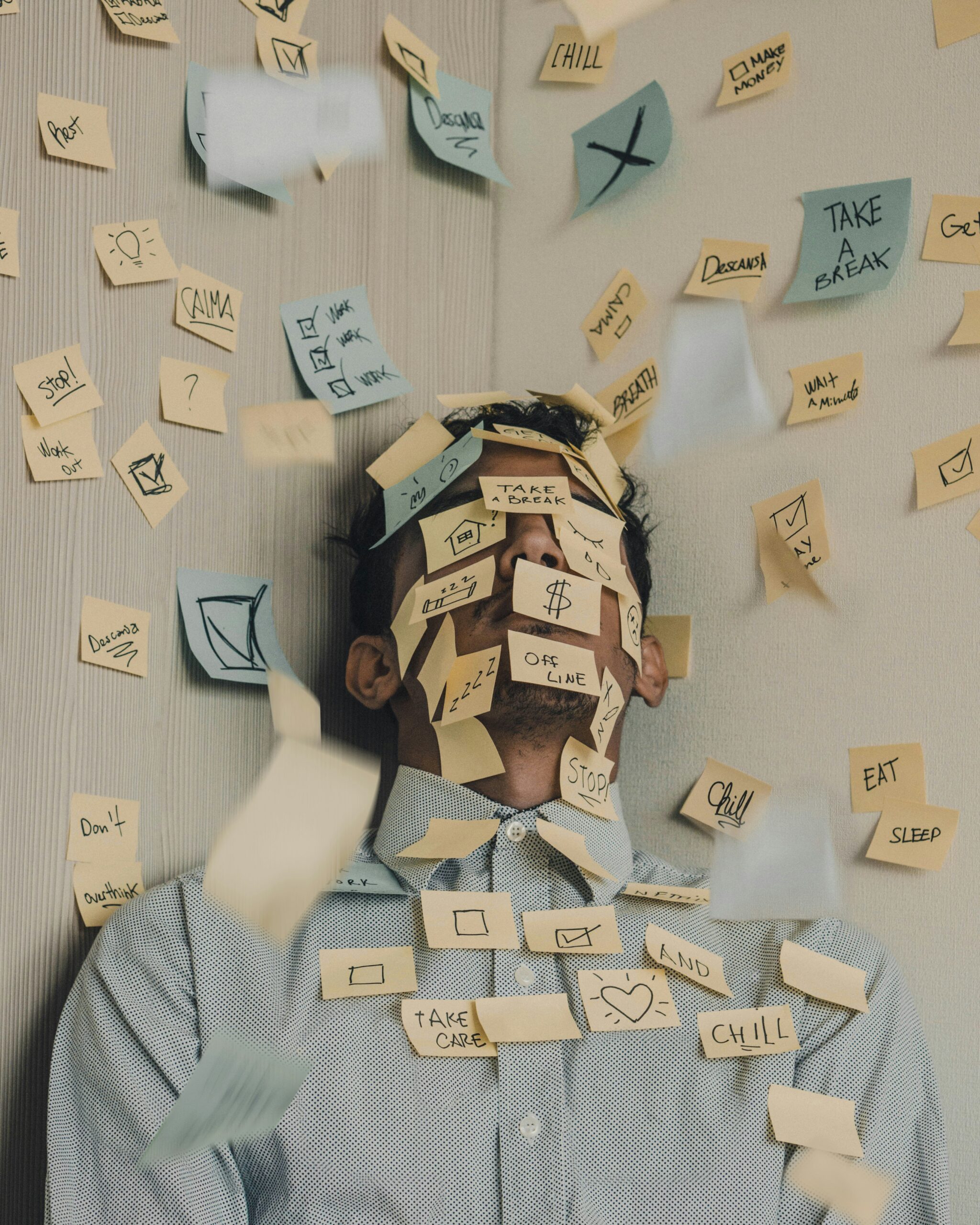 Stressed man surrounded by sticky notes showing reminders to rest, breathe, and take a break, illustrating completing the stress cycle.